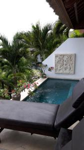 a swimming pool with a couch and palm trees at Villa Atas Lembongan in Nusa Lembongan