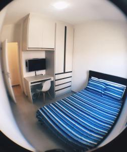 a bedroom with a bed and a desk with a monitor at Apartamento Completo em Cotia - SP in Cotia