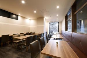 comedor con mesas y sillas de madera en Sotetsu Fresa Inn Chiba Kashiwa en Kashiwa