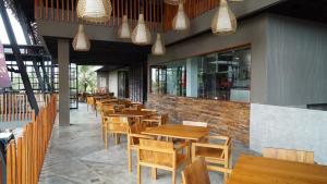 una fila de mesas y sillas de madera en un restaurante en ILA Villa Ubud, en Ubud