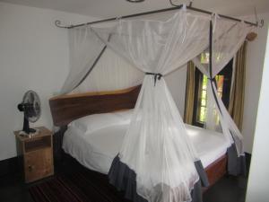 a bedroom with a bed with a canopy at Precious Guesthouse in Entebbe