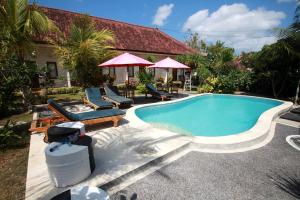 a swimming pool with chairs and a house at Rambo Homestay in Uluwatu