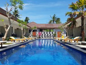 a swimming pool with benches and palm trees at Villa Pine Tree in Gili Trawangan