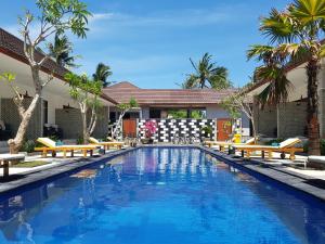 una piscina con bancos y palmeras en Villa Pine Tree, en Gili Trawangan