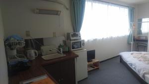 a bedroom with a bed and a desk with a microwave at Weekly Mansion Ise Annex in Ise