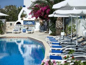 a swimming pool with lounge chairs and umbrellas at Polikandia Hotel in Chora Folegandros