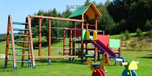 a playground with colorful equipment in the grass at Bieszczady Sosnowa Aleja in Baligród