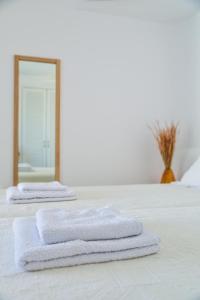 duas toalhas numa cama em frente a um espelho em Cavos em Ayios Sostis