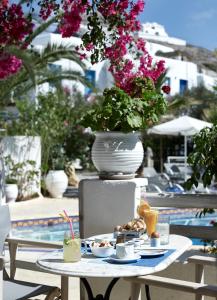 une table avec une assiette de nourriture et un vase avec des fleurs dans l'établissement Polikandia Hotel, à Folégandros