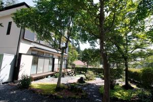 una casa con un banco y árboles delante de ella en Midorian en Nikko