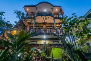 een hoog gebouw met een balkon en planten bij Yoga's House in Ubud