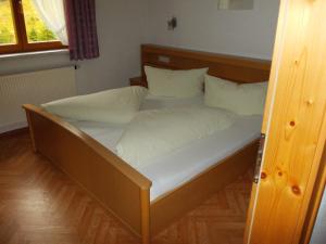 a bed with white sheets and pillows in a room at Haus Schoderböck in Sankt Leonhard im Pitztal