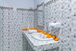 een badkamer met een witte wastafel met oranje bloemen bij Yoga's House in Ubud