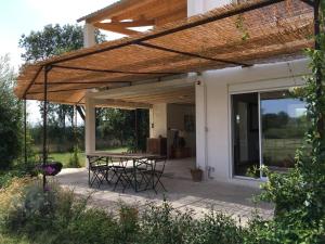 un patio con mesa y sillas bajo una pérgola en Domaine Limouzy, en Narbona