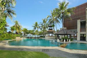 a swimming pool in front of a building with palm trees at Candi Beach Resort & Spa in Candidasa
