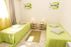 2 camas en una habitación con sábanas verdes en A La Maison De Nani, en Saint-Paul