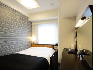 um quarto com uma cama, uma secretária e uma janela em APA Hotel Asakusa Kaminarimon em Tóquio