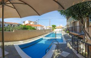 een zwembad met een parasol naast een gebouw bij Angela Apartments in Kokkari