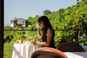 una mujer sentada en una mesa bebiendo un trago en Agriturismo due Carpini, en Valdobbiadene