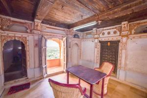 Habitación con mesa, 2 sillas y TV. en Hotel Suraj, en Jaisalmer