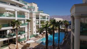 Blick auf ein Hotel mit Palmen und Pool in der Unterkunft City Resort Palmore in Eilat