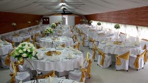 a large room filled with tables with white table settings at Pensiunea ,,La struti" in Tîrgu Neamţ