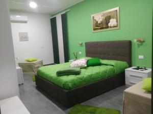 ein grünes Schlafzimmer mit einem Bett mit einer grünen Decke in der Unterkunft B&B La Grotta in Nicolosi