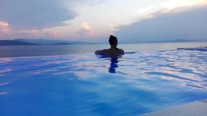 a man sitting in a swimming pool looking out at the water at Notus Villa in Chorto