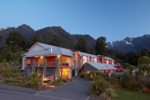 福克斯冰川Te Weheka Boutique Hotel的一座以群山为背景的大楼