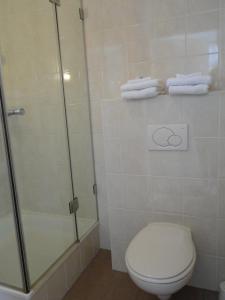 a bathroom with a shower and a toilet and towels at Hotel De Lange Jammer in Lelystad