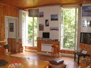 a living room with a television and large windows at Beau Soleil in Eaux-Bonnes