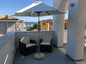 a patio with two chairs and an umbrella on a balcony at Archiammare Sea in San Lorenzo