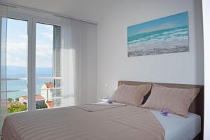 a white bedroom with a bed and a large window at Lavander Apartments Omiš in Duće