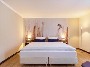 a bedroom with a large white bed with blue pillows at Aquis Grana City Hotel in Aachen