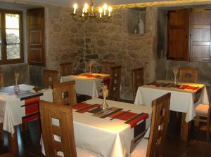un restaurante con mesas y sillas blancas y una pared de piedra en A Casa da Gandara en Camariñas