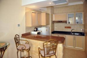 a kitchen with a counter and chairs and a sink at Palm Beach Piazza Apart hotel Sahl Hasheesh in Hurghada