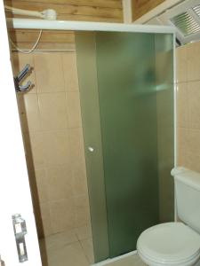 ein Bad mit einer Glastür neben einem WC in der Unterkunft Casa Condomínio Boiçucanga in Boicucanga