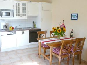 une cuisine avec une table sur laquelle est posé un vase de tournesols dans l'établissement Apartment Haus Antje, à Sankt Peter-Ording