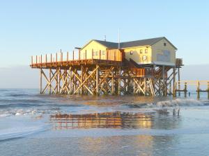 une maison au sommet d'une jetée sur la plage dans l'établissement Apartment Haus Antje, à Sankt Peter-Ording
