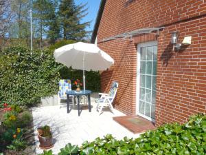 een patio met een tafel en stoelen en een parasol bij Apartment Haus Antje in Sankt Peter-Ording