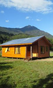 a house with a solar roof on top of a field at Cabañas piedra Alta, Huilo Huilo in Panguipulli