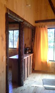 a kitchen with a counter and two windows in a cabin at Cabañas piedra Alta, Huilo Huilo in Panguipulli