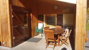 een houten veranda met een tafel en stoelen op een terras bij Chalet au bord du lac de Longemer in Xonrupt-Longemer