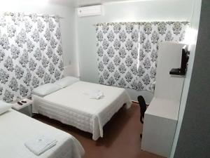 a hotel room with two beds and a chair at Giroto Hotel in Realeza