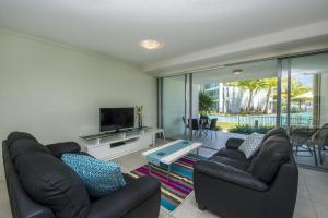 a living room with two leather couches and a television at Blue on Blue Apartment 813 in Nelly Bay