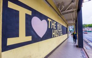 a man walking down a sidewalk next to a building with a heart sign at The Hive Singapore Hostel in Singapore