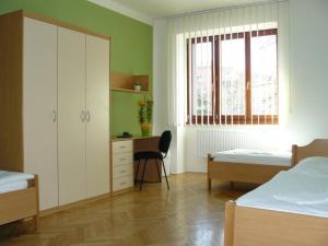 1 dormitorio con 2 camas, escritorio y ventana en Ubytovna Marie en Olomouc