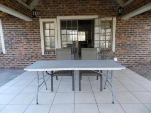 a white table with chairs in front of a brick building at Impalas Walk in Marloth Park