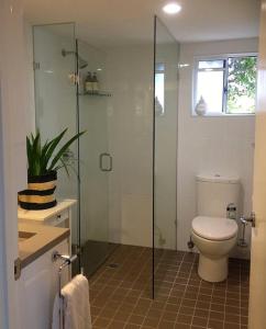 a bathroom with a toilet and a glass shower at Jacaranda House Garden Retreat in Brisbane