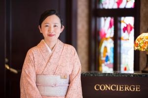 Kanazawa Hakuchoro Hotel Sanraku في كانازاوا: امرأة في رداء وردي تقف في الكنيسة